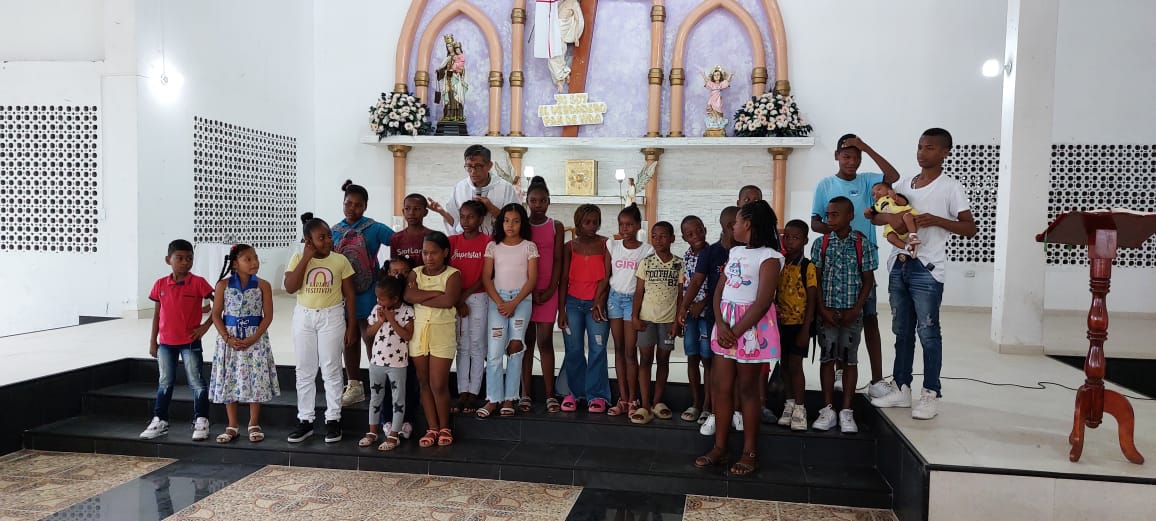 Kinder mit dem Priester am Altar, dahinter liegt der Katechetiksaal